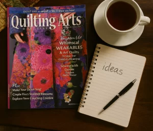quilting arts magazine with notebook and coffee